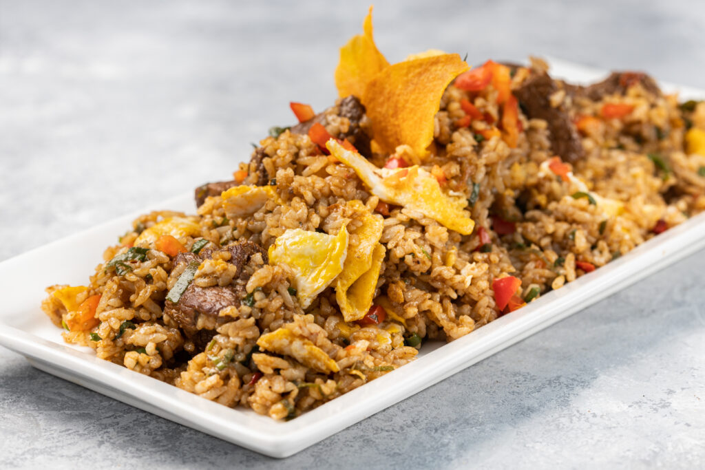 Closeup of spicy cooked rice with meat, vegetables and chips in a plate on the table